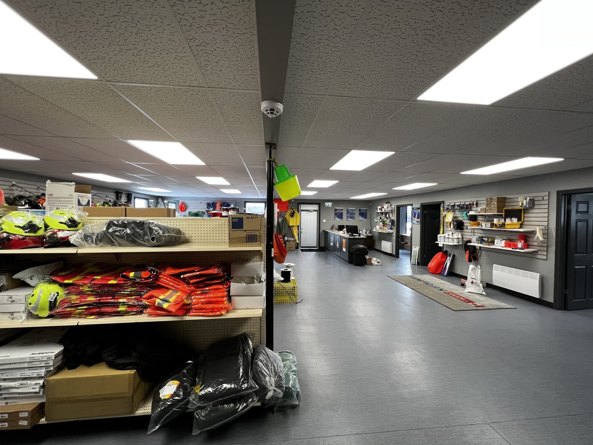The walk-in counter at the Port au Choix branch, flotation and hi-vis gear on the shelving with the service counter beyond