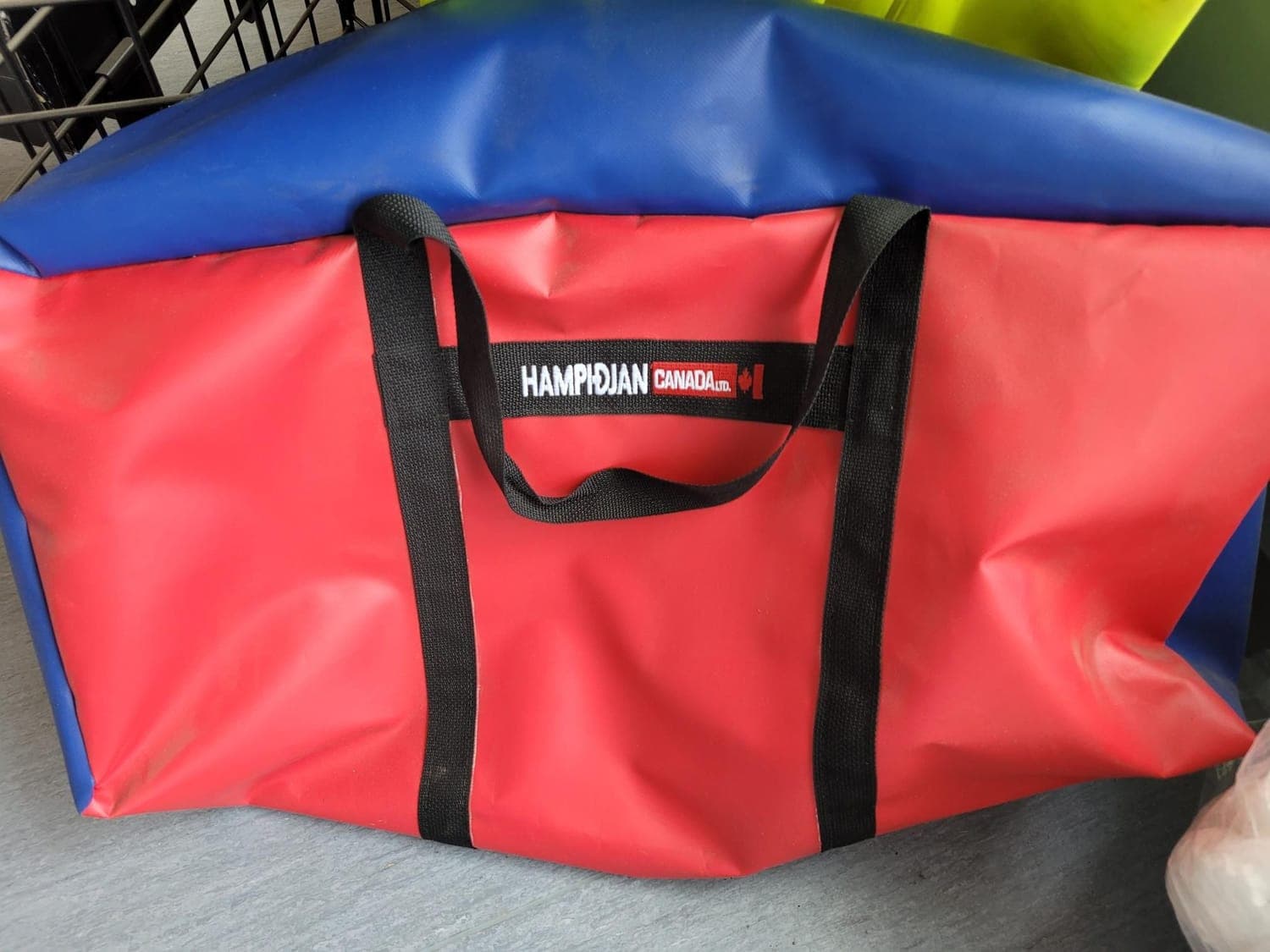 A heavy red and blue PVC bag with webbing handles carrying Hampidjan Canada branding