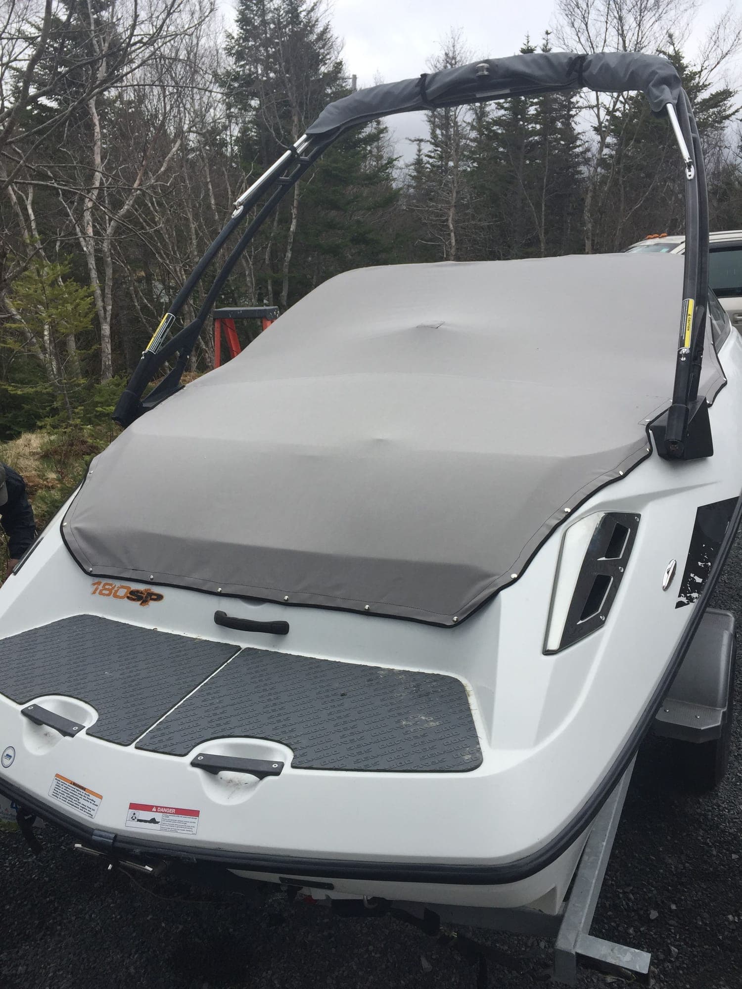 A grey fitted cover snapped down along the gunwale of a bowrider, cut around the wakeboard tower