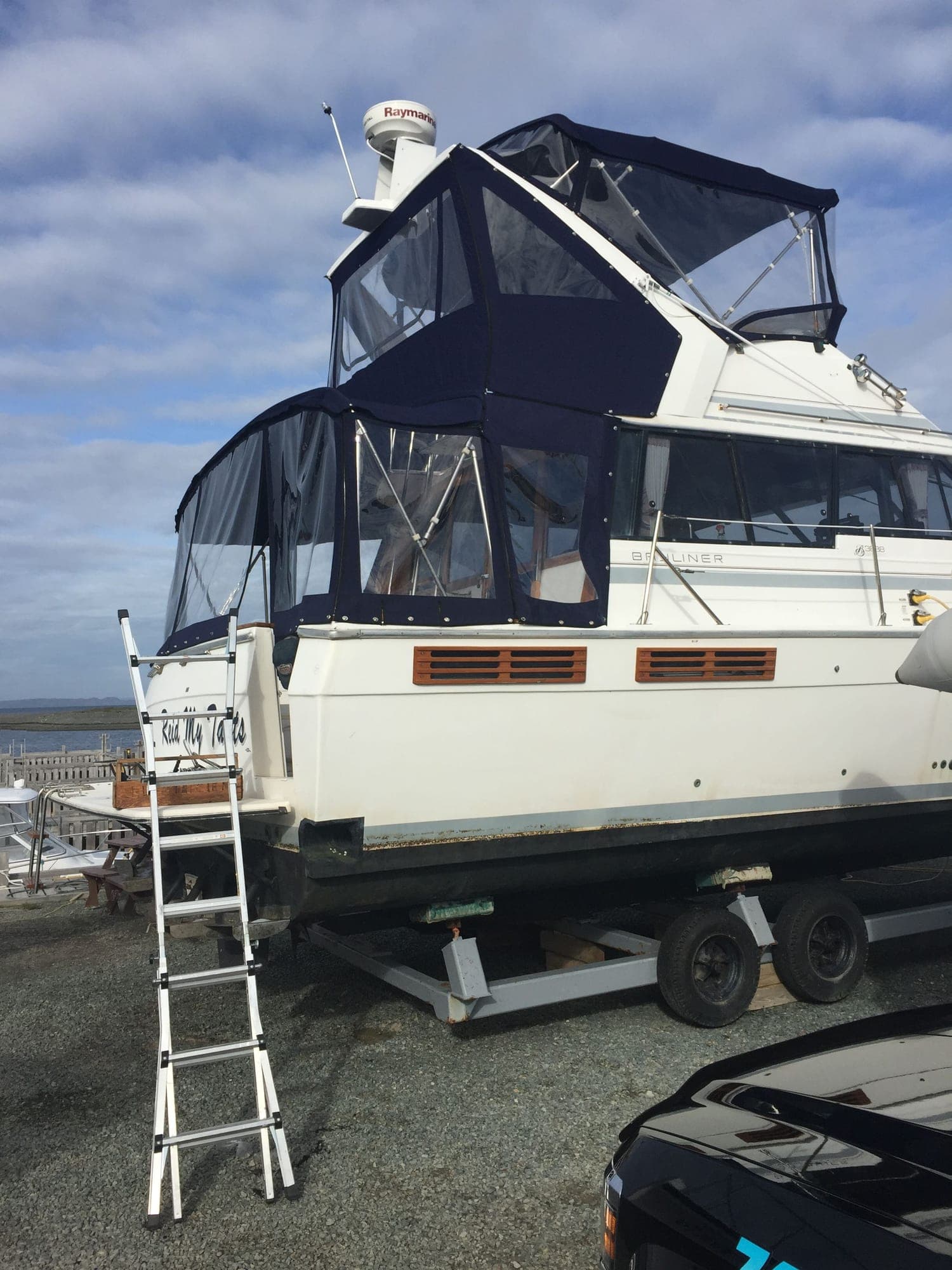 A flybridge cruiser under a full navy enclosure with clear panels, aft curtains zipped in place