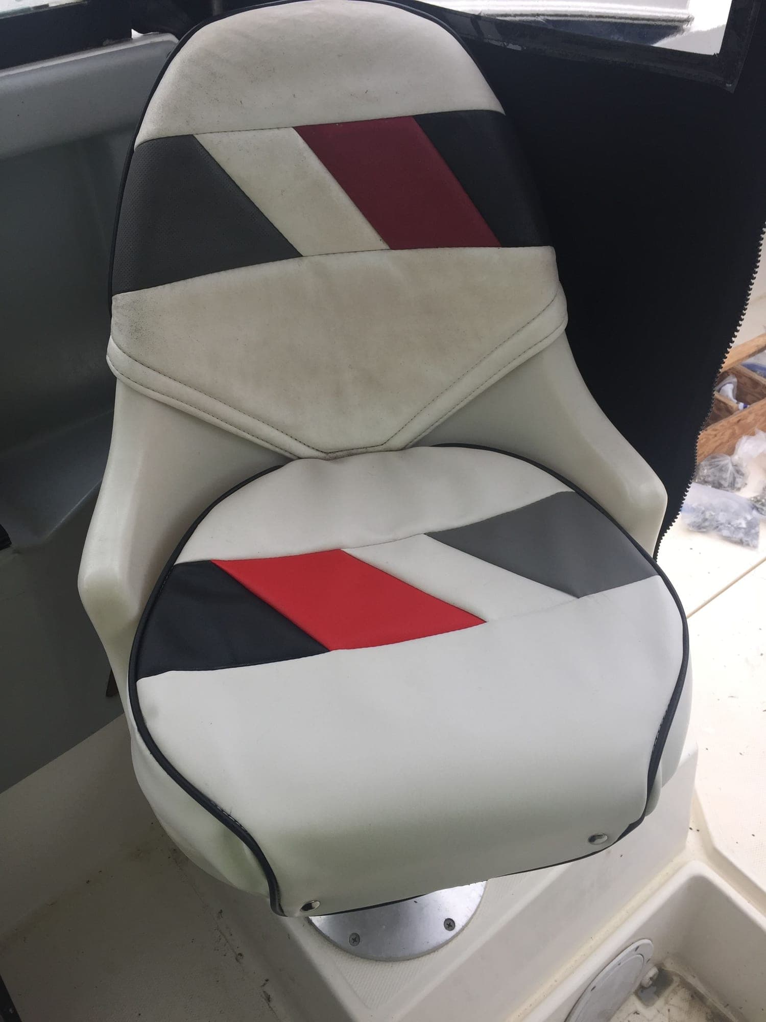 A boat helm seat in white, grey, red and black panelled upholstery, the lower cushion freshly recovered beneath the original back