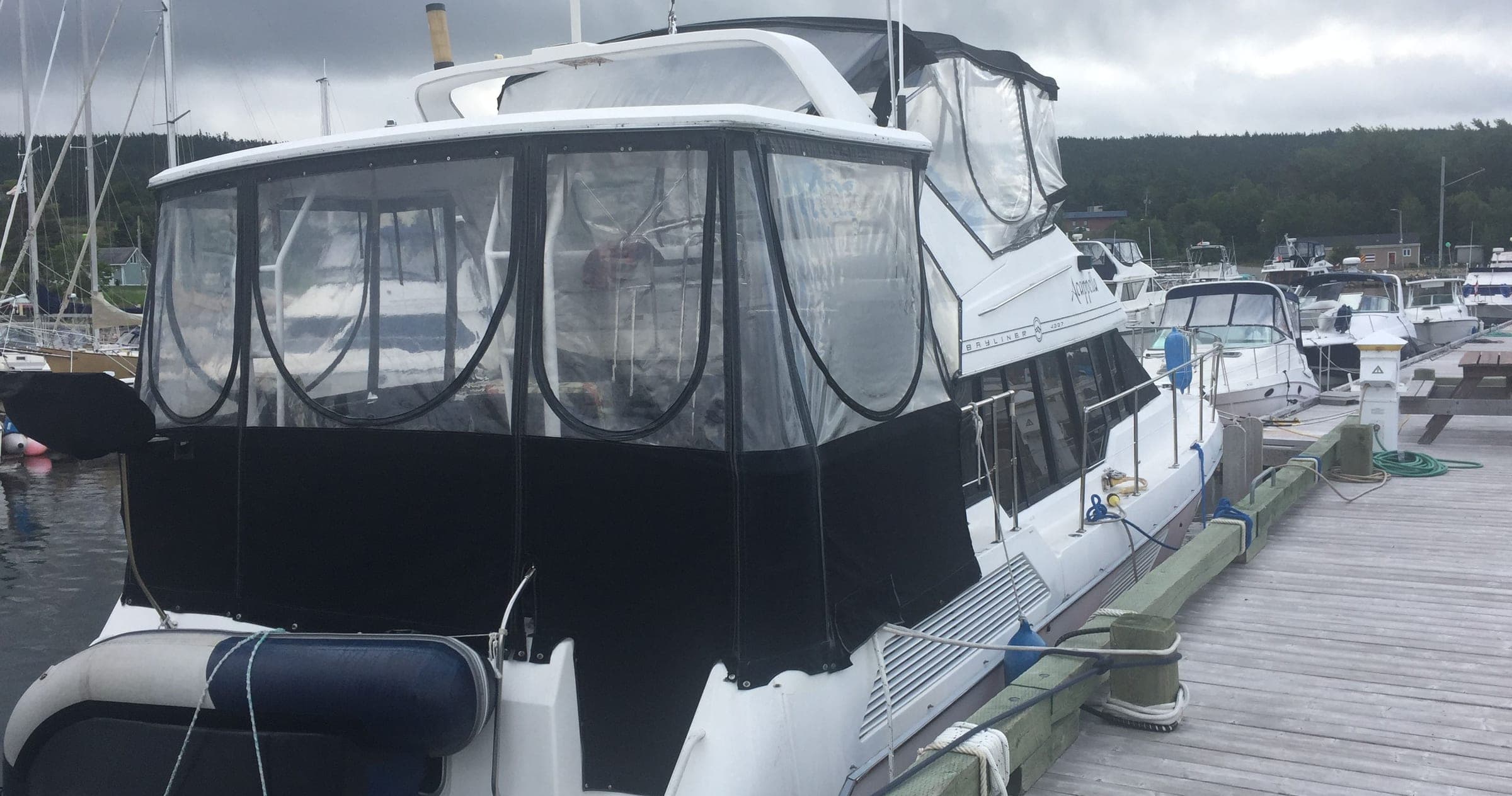 A motor yacht at the dock under a full black camper enclosure with clear panels