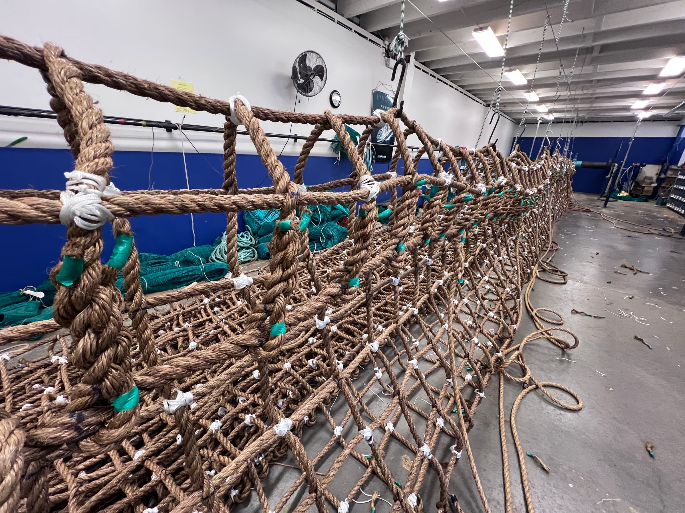 A large rope-mesh structure under construction on the loft floor
