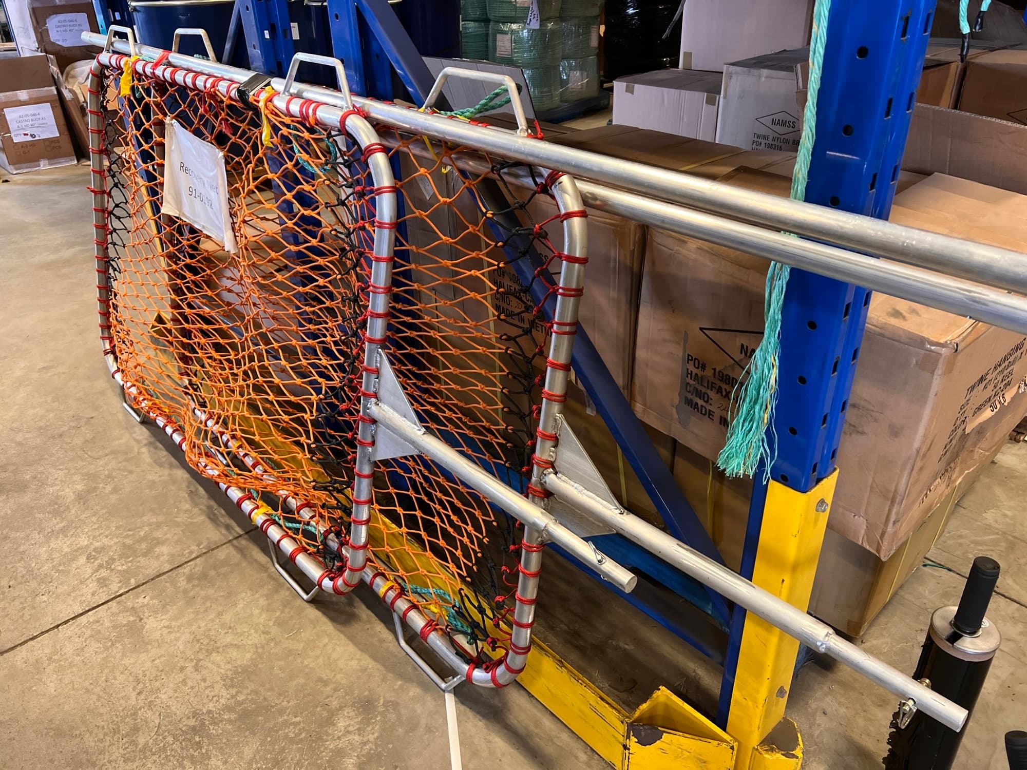 Orange recovery nets on aluminium frames stacked against racking in the shop