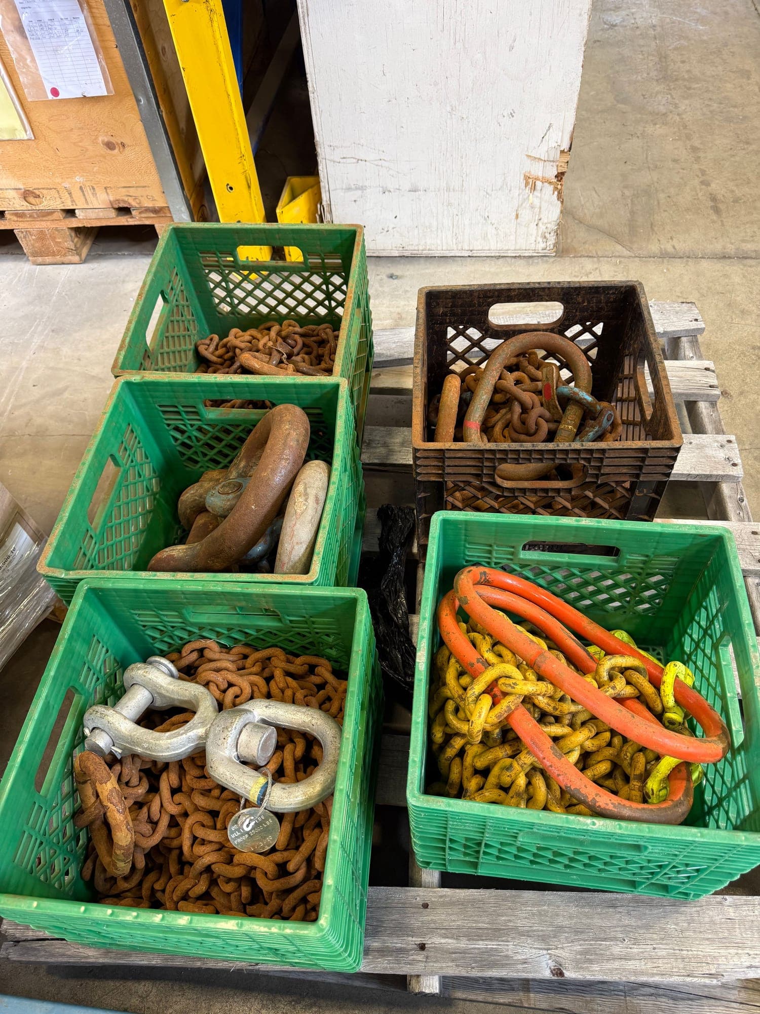 Crates of chain, master links and shackles on a pallet, sorted and waiting to be gone through