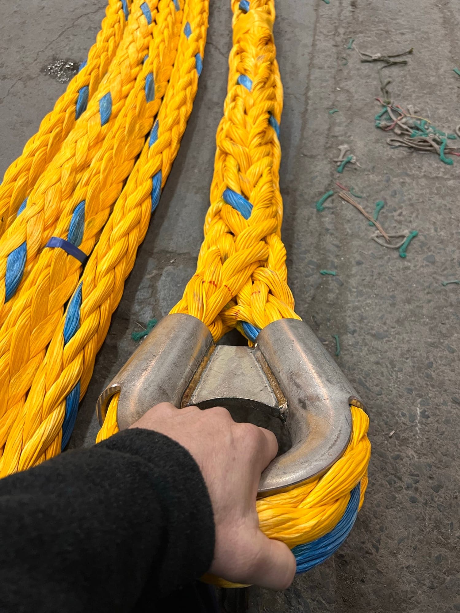 A hand on the heavy steel thimble spliced into a yellow Prima bridle leg, two more legs running away along the floor