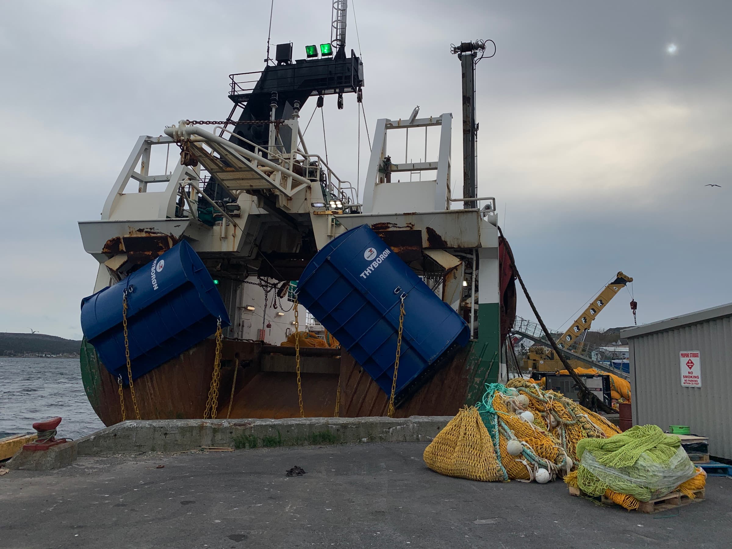 A pair of blue Thyborøn doors hung on the gantry of a stern trawler alongside our wharf, its netting bundled on the apron