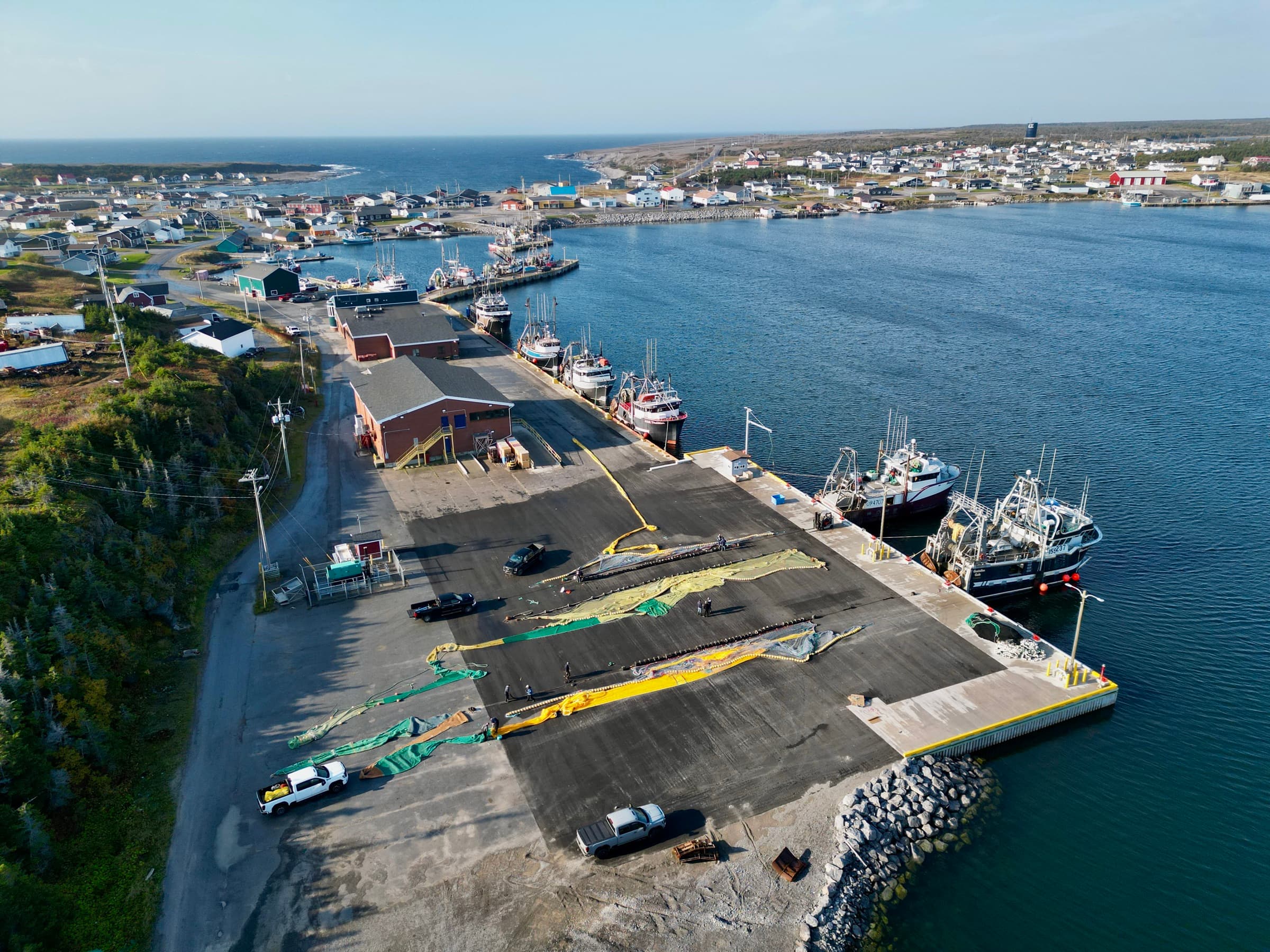A trawl laid out along the wharf beside the fleet in a Newfoundland harbour, seen from above