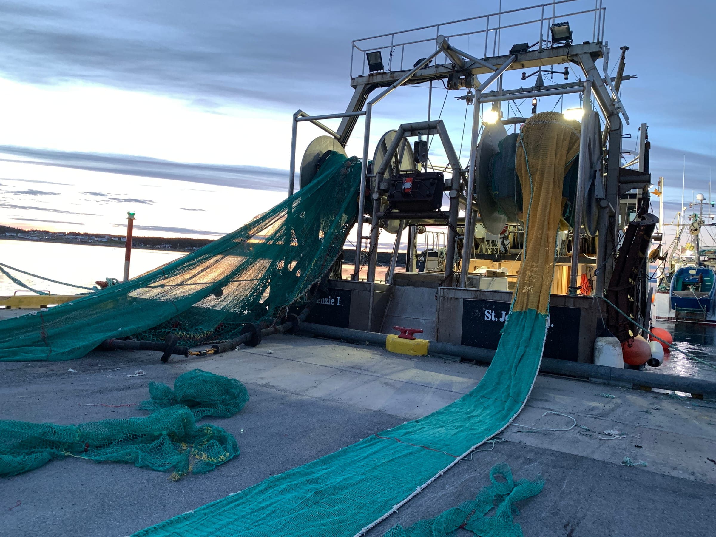 A trawl running off a vessel's net drums and laid out down the wharf at dusk