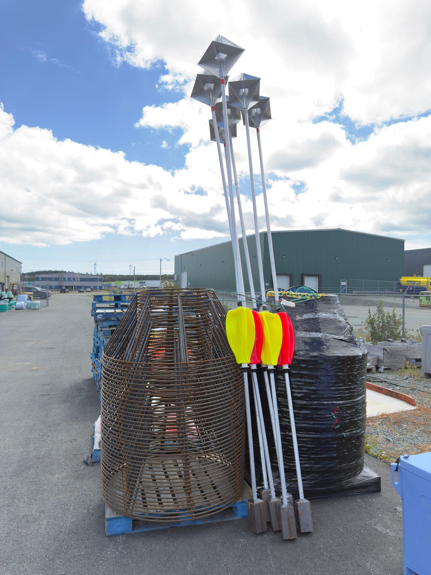 A pallet of bare steel crab frames in the yard beside highflyer poles with radar reflectors and floats